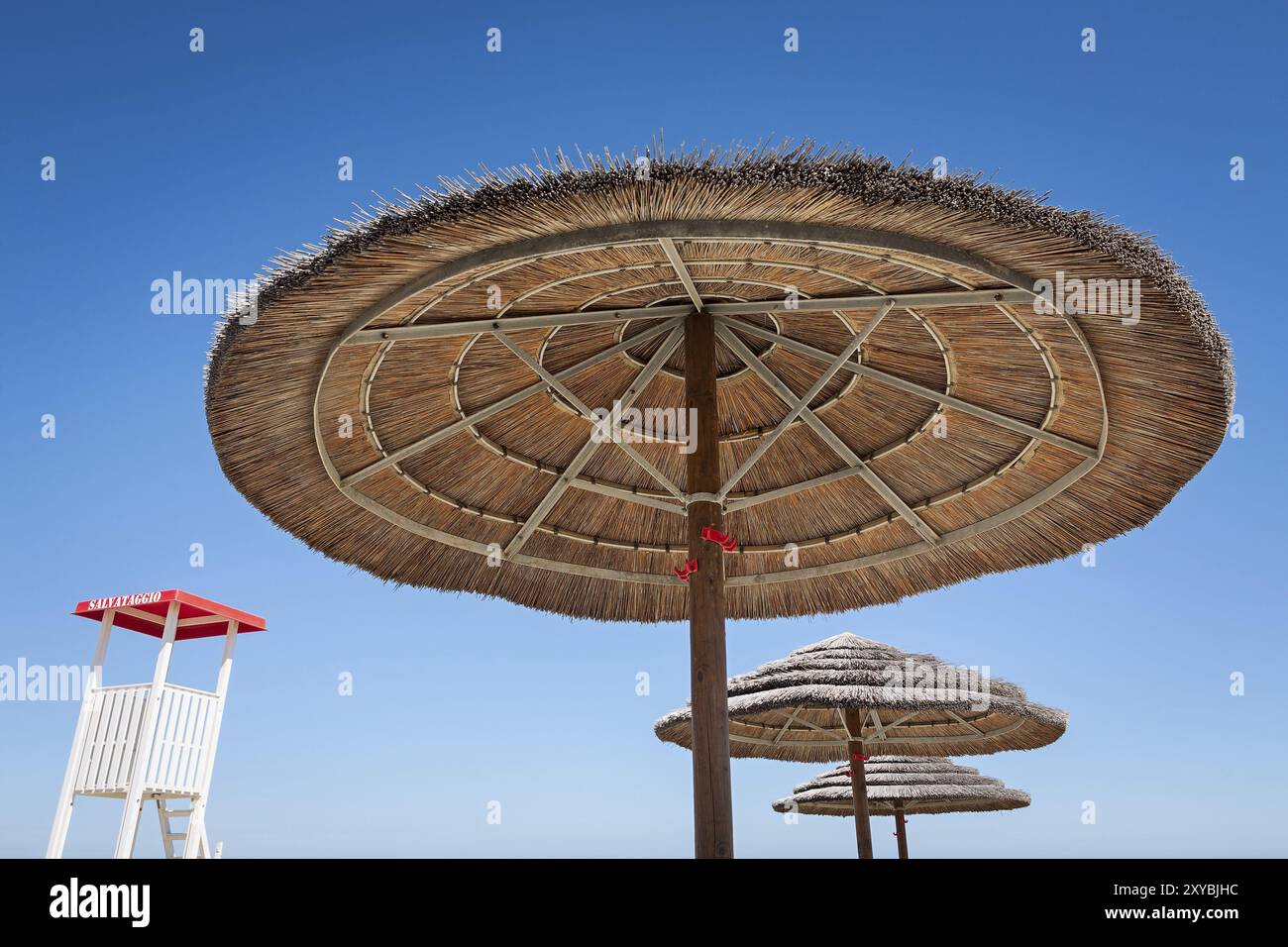 Life guard und drei Sonnenschirmen auf blauem Himmel Hintergrund Stockfoto