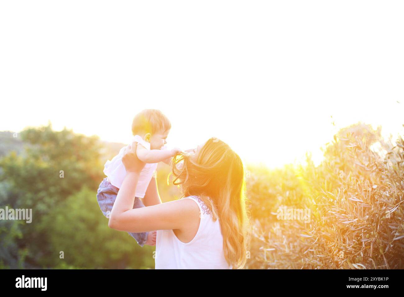 Junge, glückselige Frau mit Baby im Freien. Familienurlaub Stockfoto