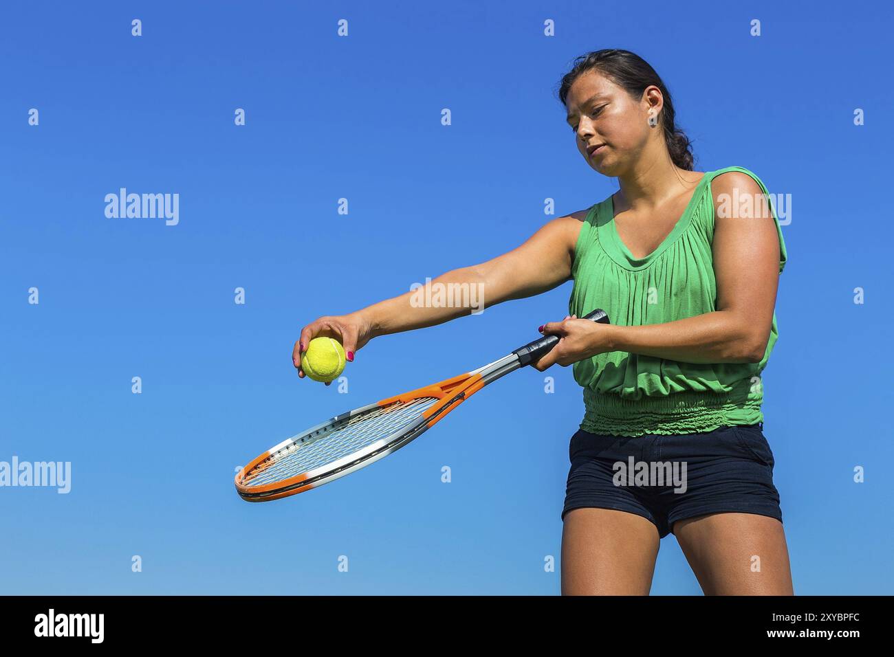 Junge kolumbianische Frau mit Tennisschläger und Ball gegen den blauen Himmel Stockfoto