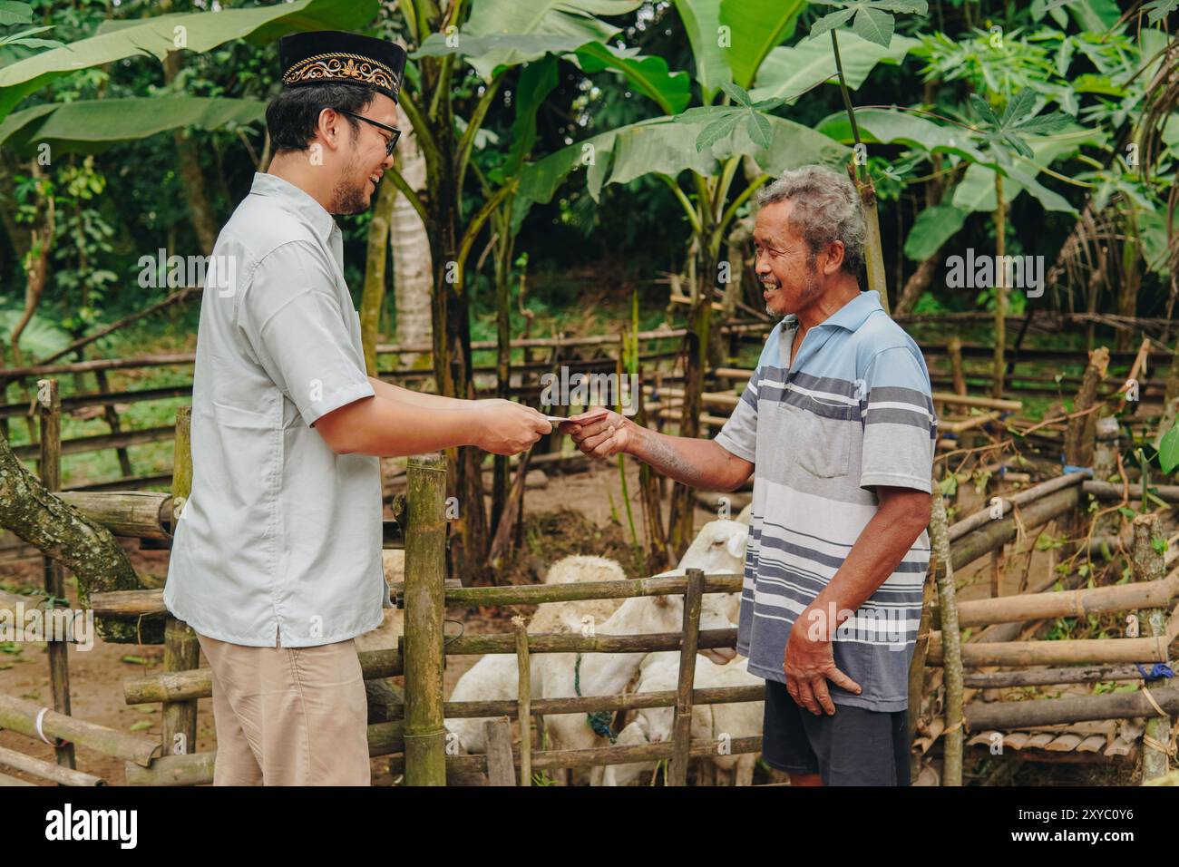 Junger asiatischer muslimischer Mann schließt Deal-Transaktion ab und macht Handschlag mit dem Viehzüchter, der Viehziegen für Opfer kauft. EID Al Adha Konzept. Stockfoto
