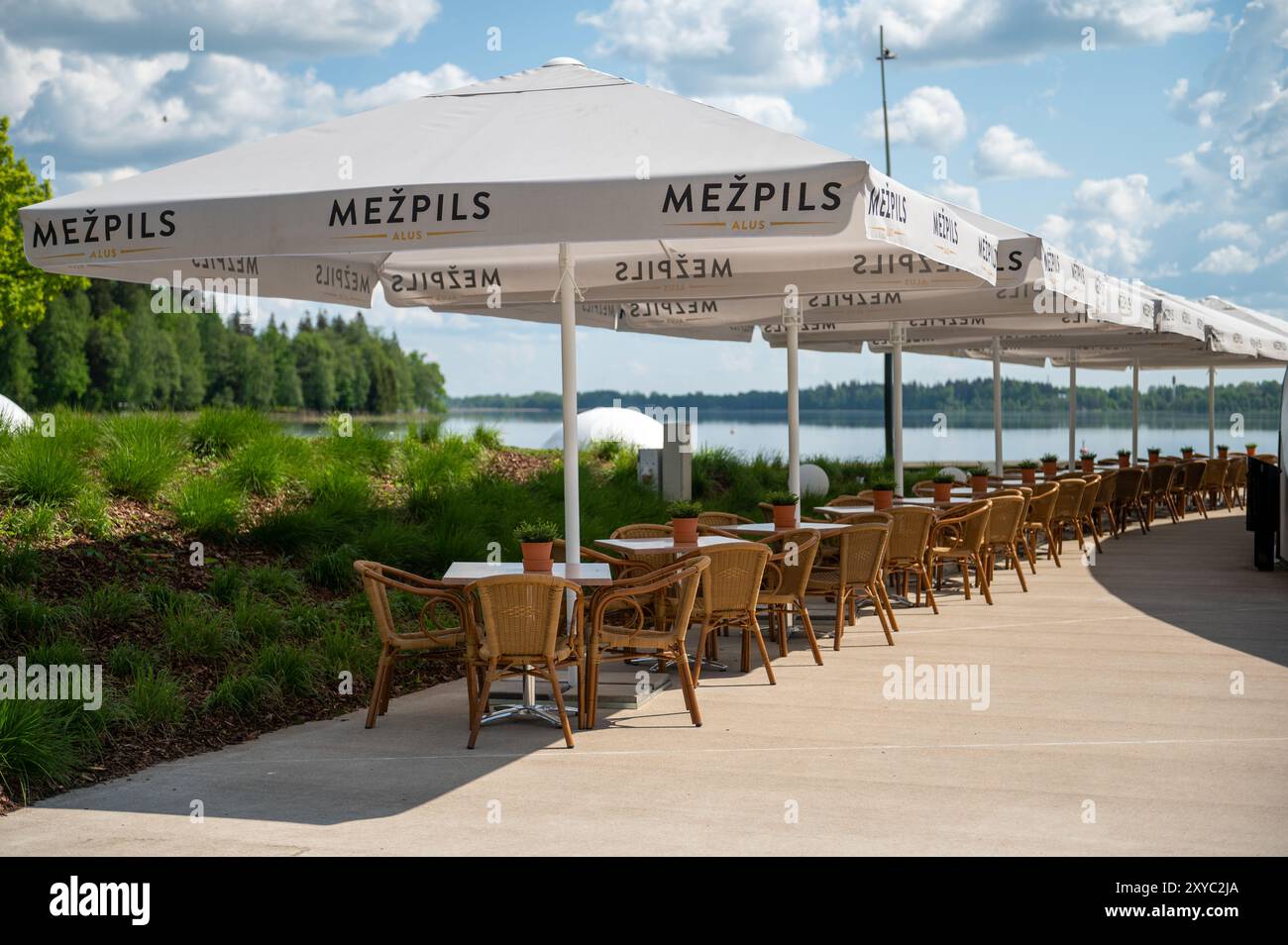 Aluksne, Lettland - 24. Mai. 2023: Gemütliches Café am Wasser mit Sonnenschirmen und Tischen entlang des Sees an einem sonnigen Nachmittag Stockfoto