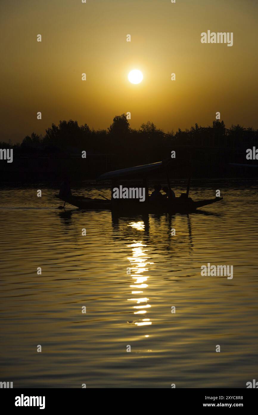 Ein überdachtes Boot macht eine Bootstour bei Sonnenuntergang auf dem Dal-See, einem berühmten Touristenziel in Srinagar, Kaschmir, Indien, Asien Stockfoto