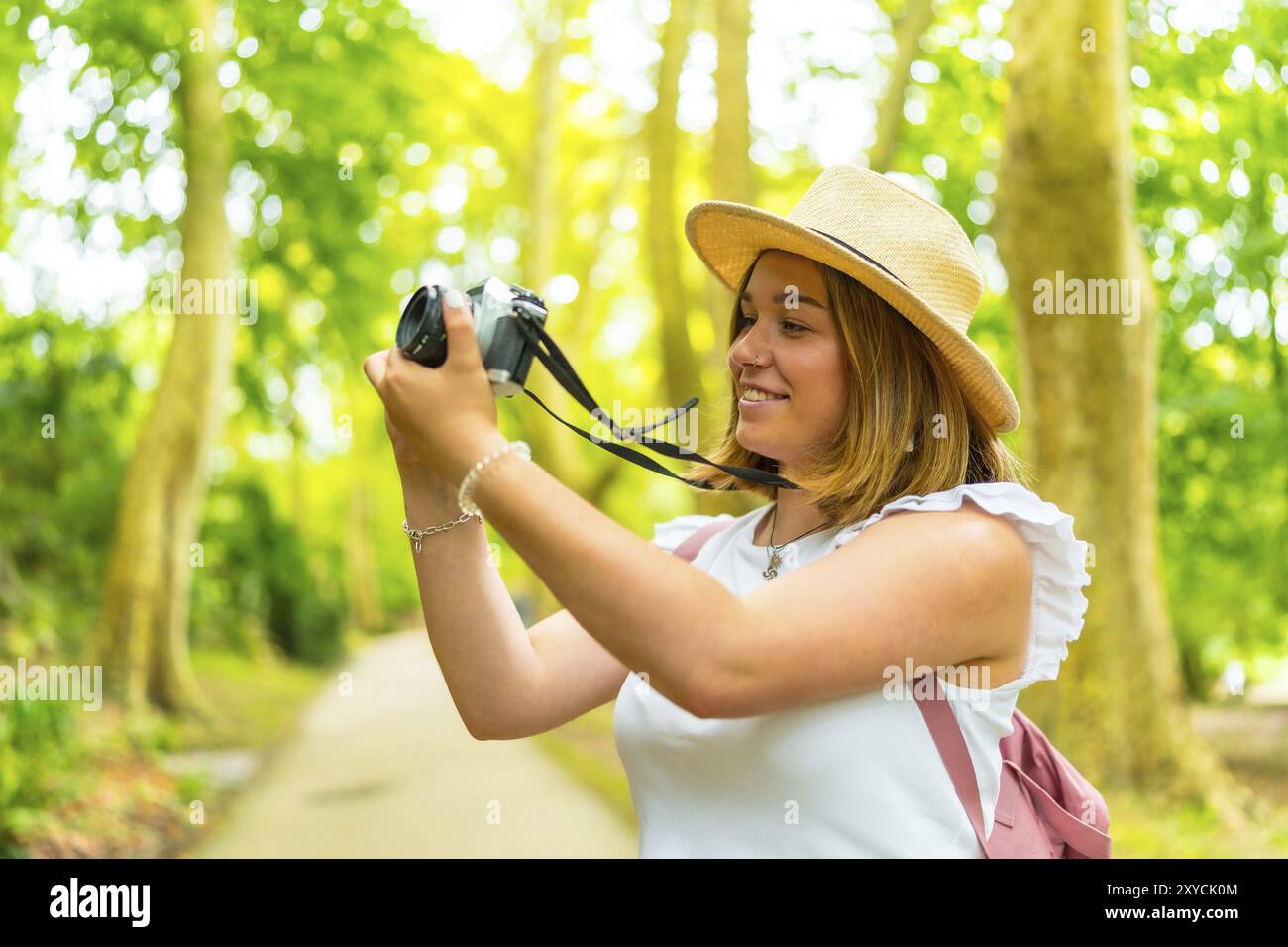 Nahaufnahme einer kaukasischen jungen, fröhlichen Frau, die mit der Kamera durch den Wald wandert Stockfoto