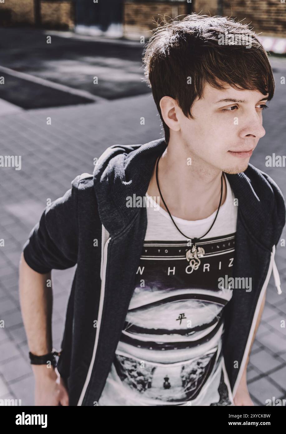 Junger erwachsener Rockmusiker, der wegschaut, Seitenansicht, Sänger trägt ein blaues Sweatshirt und T-Shirt, steht, braune Haare und Bart Stockfoto