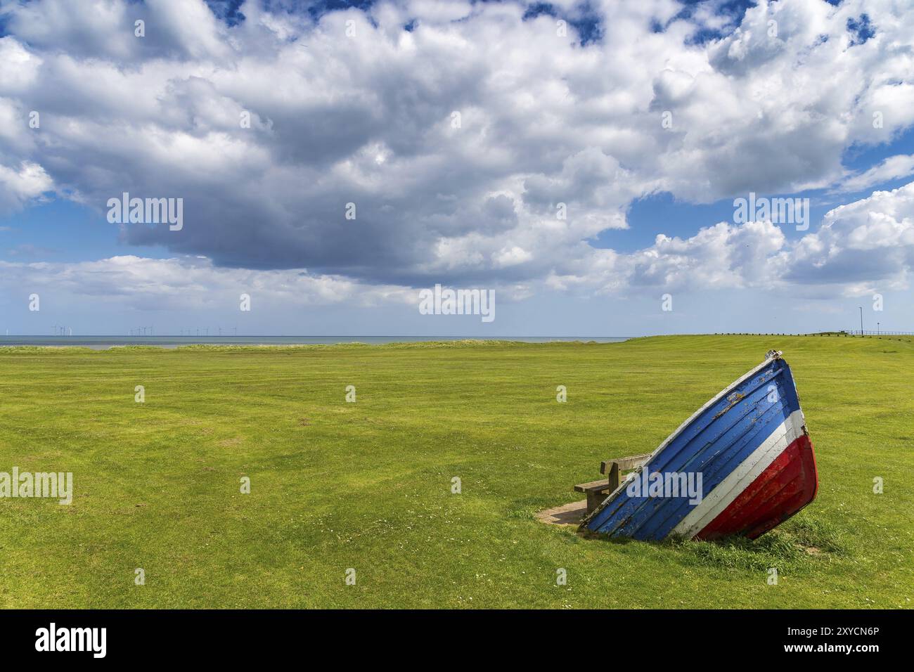Eine Bank mit Windschutz durch ein vergrabenes Boot, gesehen in Withernsea, East Riding of Yorkshire, England, Großbritannien Stockfoto