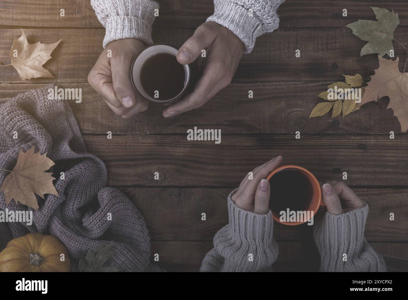 Verliebtes Paar holding Tasse Tee oder Kaffee am Tisch mit Herbstlaub bedeckt Stockfoto