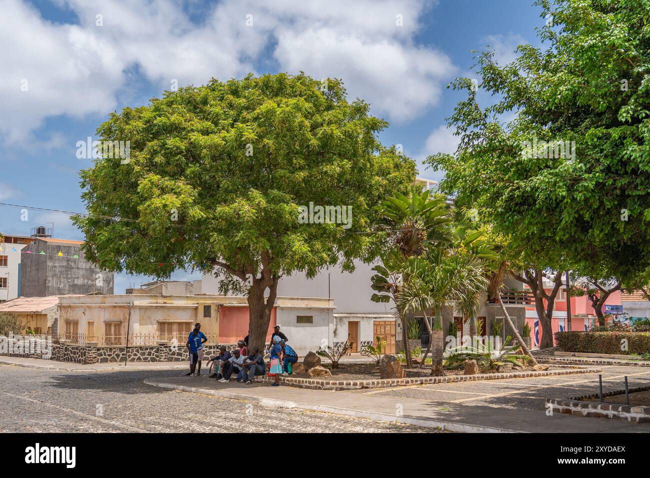 Tarrafal, Kap Verde - 10. Juni 2024: Blick auf die Stadt Tarrafal mit einer Gruppe von Menschen im Schatten eines Baumes auf der Straße auf der Insel Kap Verde Stockfoto