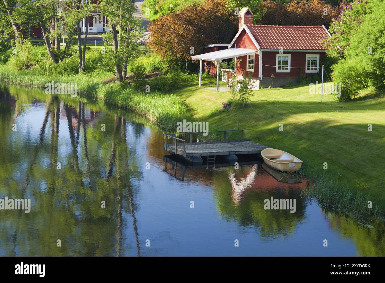 Traditionelles schwedisches Holzhaus in kupferroter Farbe am Ufer des Eman bei Hoegsby, Smaland, Südschweden. Altes rotes Holzhaus in t Stockfoto