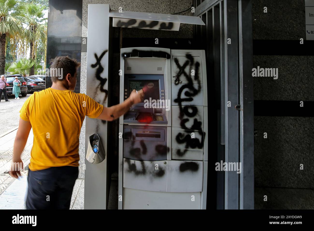 Beirut, Libanon. August 2020. Ein libanesischer Einleger besprüht einen Geldautomaten einer lokalen Bank in Beirut, der von Einlegern während eines Protestes angegriffen wurde, um ihr eigenes Geld zu fordern. Während·sich die lähmende Wirtschaftskrise des winzigen Mittelmeerstaates weiter verschärft, haben sich eine wachsende Zahl libanesischer Einleger dafür entschieden, in Banken einzubrechen und ihre eingeschlossenen Ersparnisse gewaltsam abzuziehen. Marwan Naamani/dpa/Alamy Live News Stockfoto