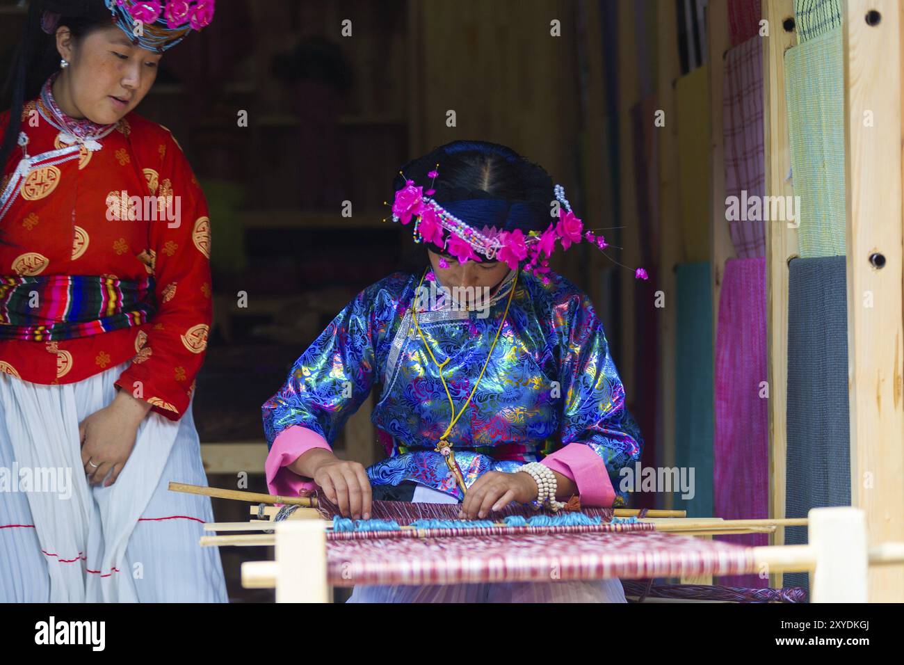 Lijiang, China, 2. Oktober 2007: Eine Naxi ethnische Minderheit, die in traditioneller Tracht gekleidet ist und Textilien mit einem Webstuhl in der Altstadt von Lijiang, Yunnan, webt. Stockfoto