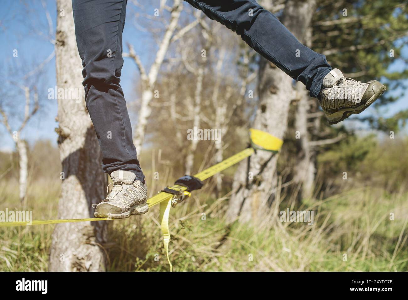 Close-up Slacklining ist eine Praxis des Balancierens, bei der üblicherweise Nylon- oder Polyestergewebe zwischen zwei Ankerpunkten verwendet werden. Menschen gehen Stockfoto