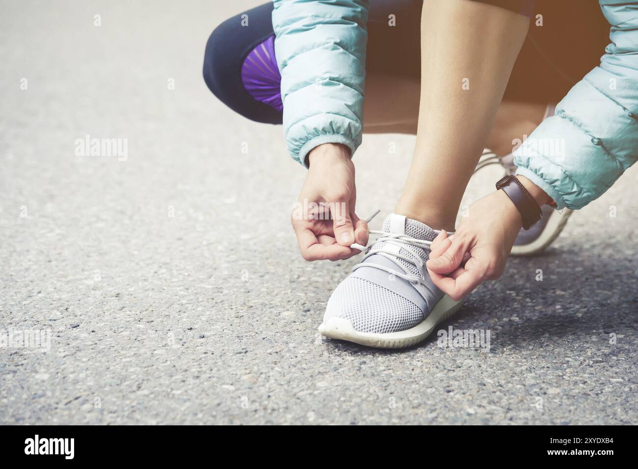 Läuferin, die Schnürsenkel bindet, um ihre Schuhe auf der Straße im Park zu joggen. Laufschuhe, Schnürsenkel. Übungskonzept. Sportlicher Lifestyle. Vintage-Style Stockfoto