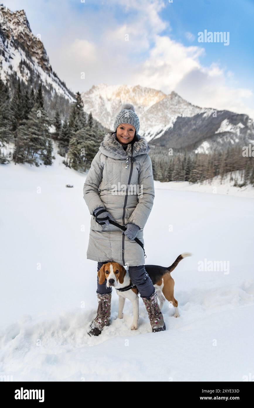 Ein junges Mädchen, das im Winter mit ihrem Beagle-Hund spaziert und beim ersten Mal Spaß auf Schnee hat Stockfoto