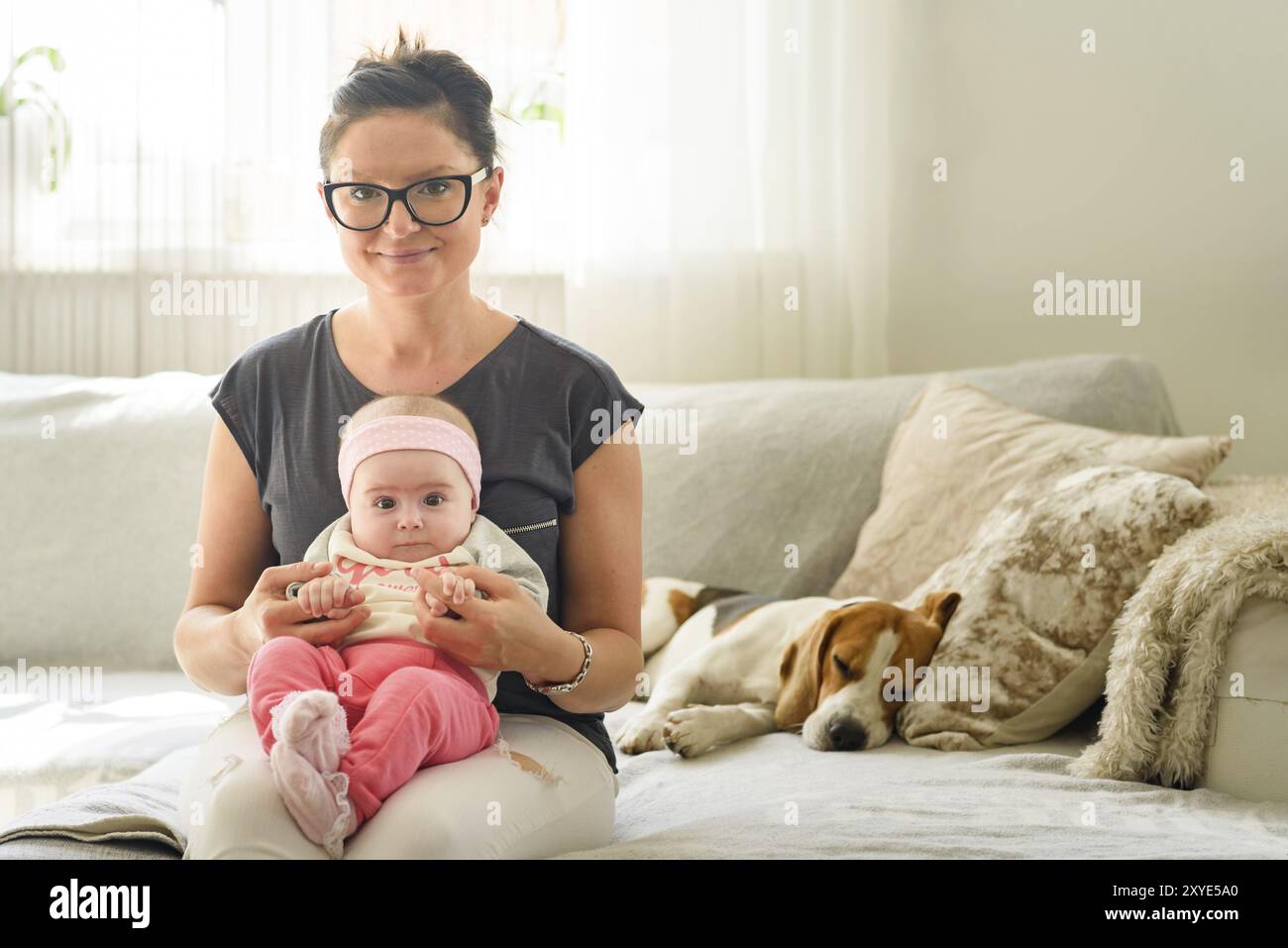 Mutter hält schöne Baby-Mädchen in hellen sonnigen Zimmer. Mutterschaft Hintergrund Stockfoto