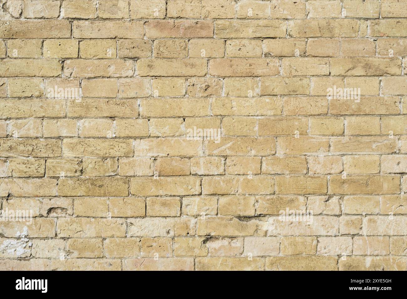 Strukturierter Hintergrund eines Steinsteins aus gelbem antediluvischem Mauerwerk. Teilweise zerstörte Wand. Backsteingrunge-Hintergrund im Vintage-Stil Stockfoto