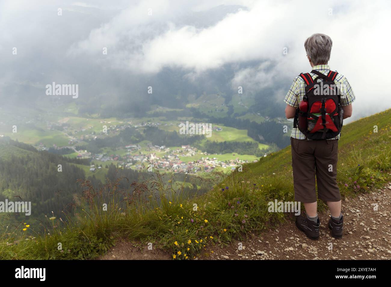 Frau, die von einem Wanderweg ins Tal schaut Stockfoto