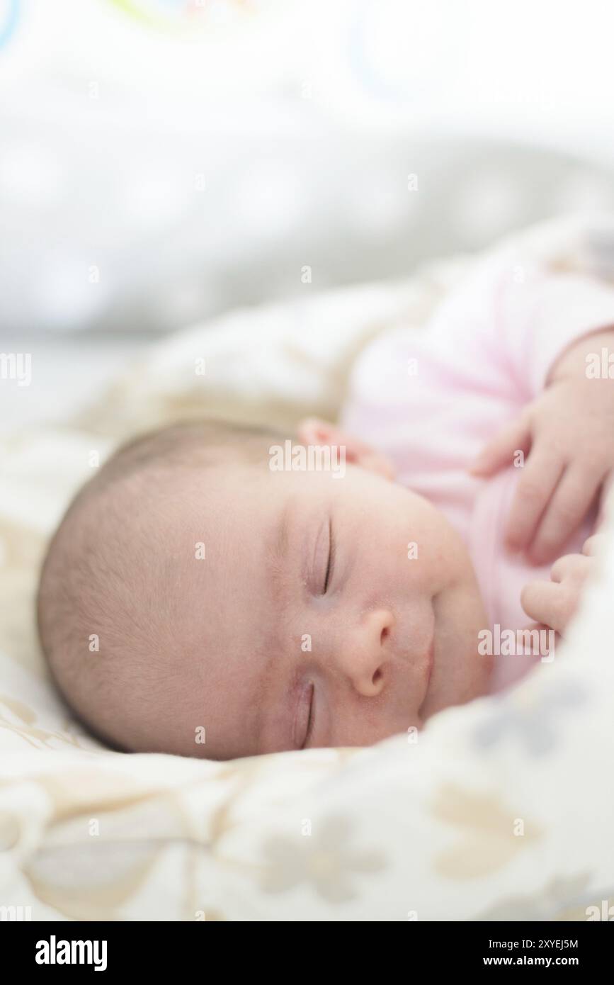 Schlafendes Neugeborenes. Süßes kleines Mädchen, eine Woche alt zu Hause. Entzückend liegend auf der Seite mit Decke bedeckt. Keine Retusche, neugeborene trockene Haut Stockfoto