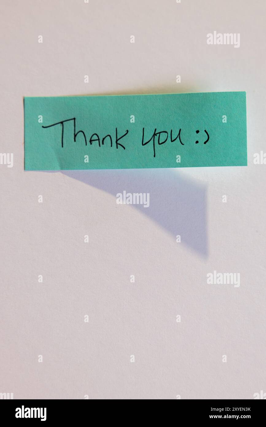 Eine blaue Haftnotiz mit den Worten „Danke“. Der Bezugshinweis wird mit Klebeband an einer weißen Wand oder Oberfläche befestigt Stockfoto
