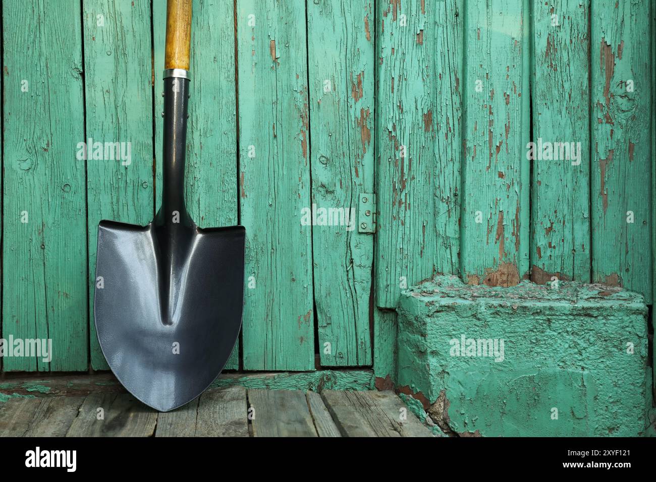 Metallschaufel in der Nähe einer türkisfarbenen Holzwand. Gartenwerkzeug Stockfoto