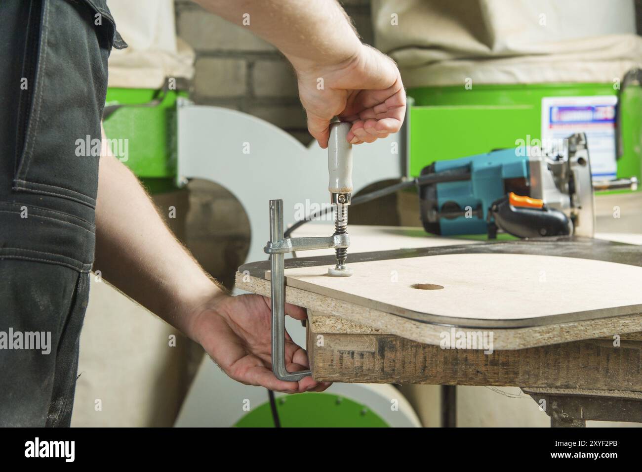 Close Up Master klemmt das Werkstück mit einer dvp-Klemme an der Werkbank und auf dem Hintergrund liegt der Handfräser von Carpentry Stockfoto