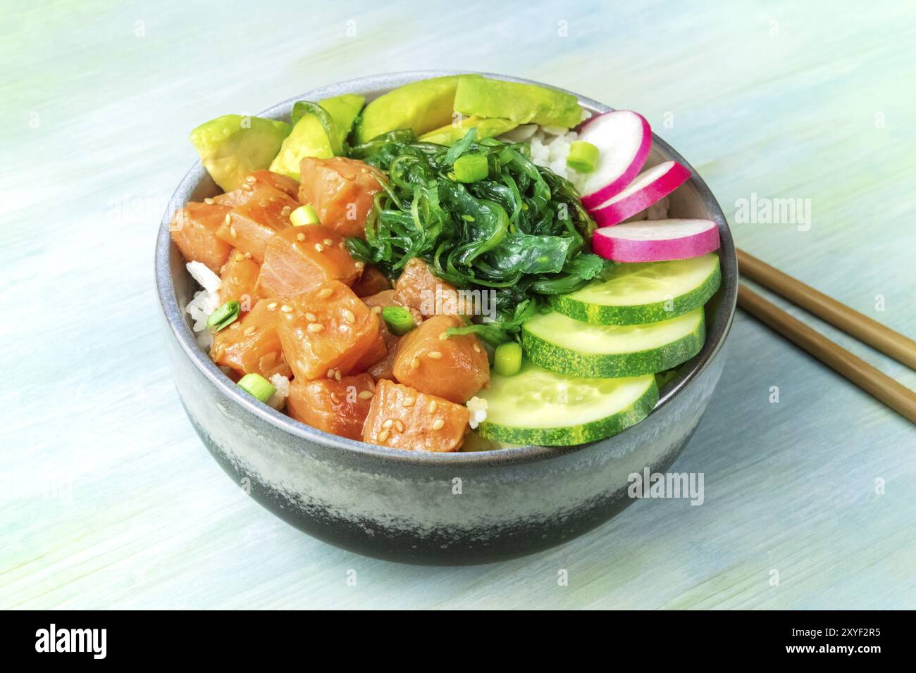 Eine Schüssel mit Lachs poke mit Avocado, Wakame und Gurke auf eine hellblaue Hintergrund Stockfoto