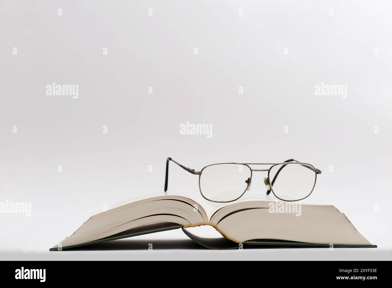 Die Brille liegt auf einem offenen Buch Stockfoto