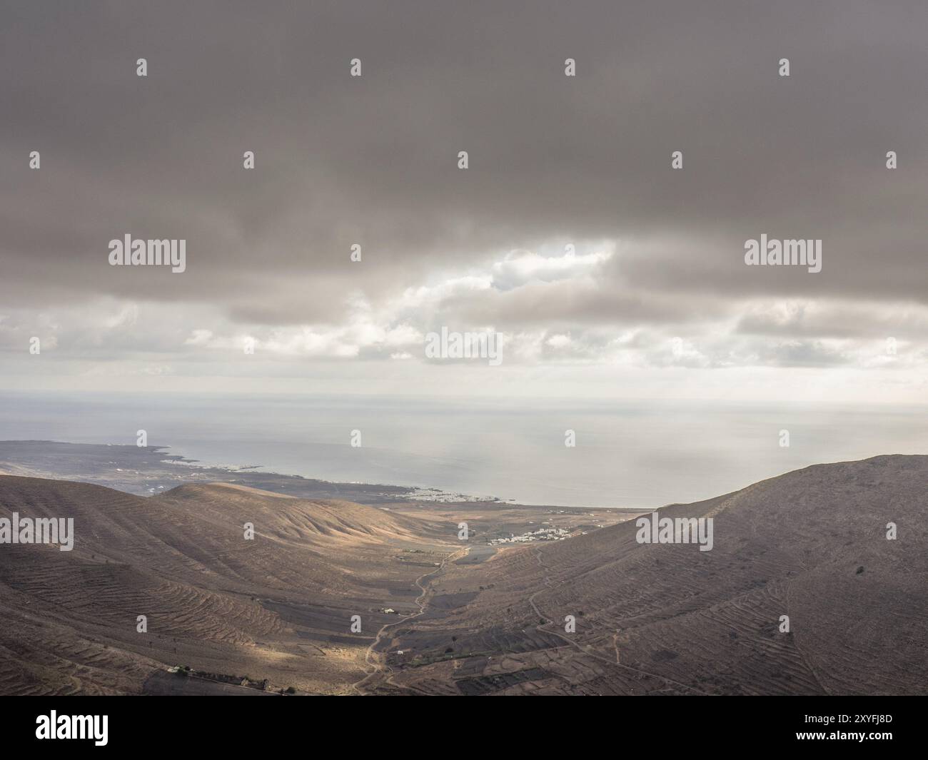 Panoramablick auf hügeliges Gelände mit bewölktem Himmel und Lichtstrahlen, die durch Wolken brechen, lanzarote, Kanarische Inseln, Spanien, Europa Stockfoto