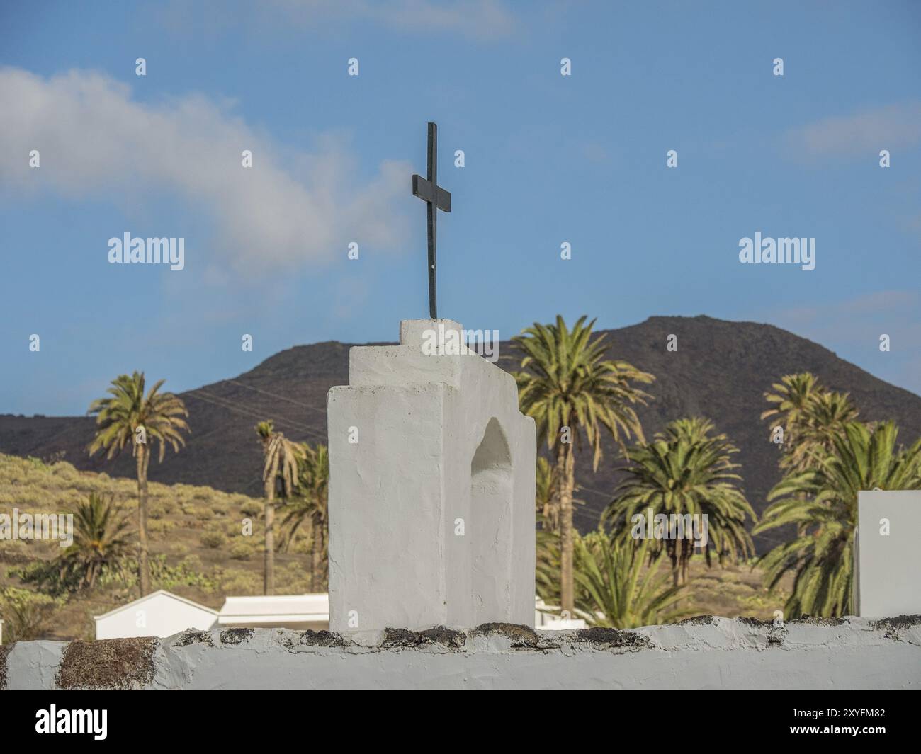 Kirche mit einem Kreuz auf der Spitze und Palmen im Hintergrund unter bewölktem Himmel, lanzarote, Kanarische Inseln, Spanien, Europa Stockfoto