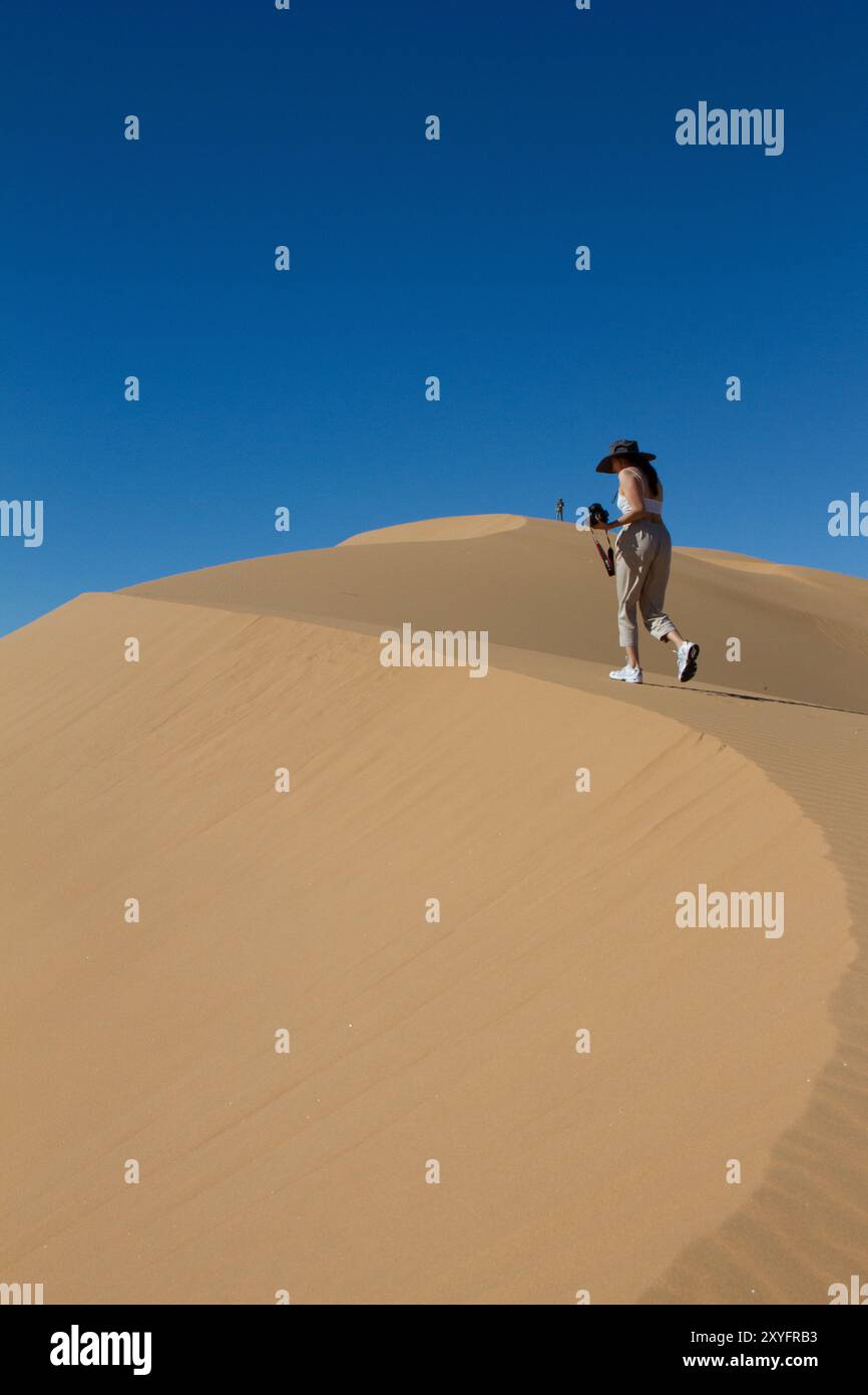 Eine Frau, die in der Wüste auf eine Düne läuft. Stockfoto