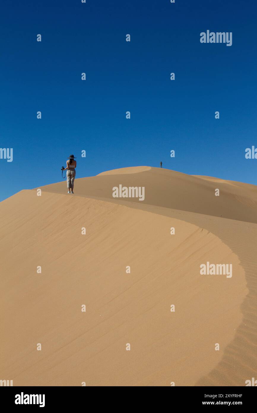 Eine Frau, die in der Wüste auf eine Düne läuft. Stockfoto