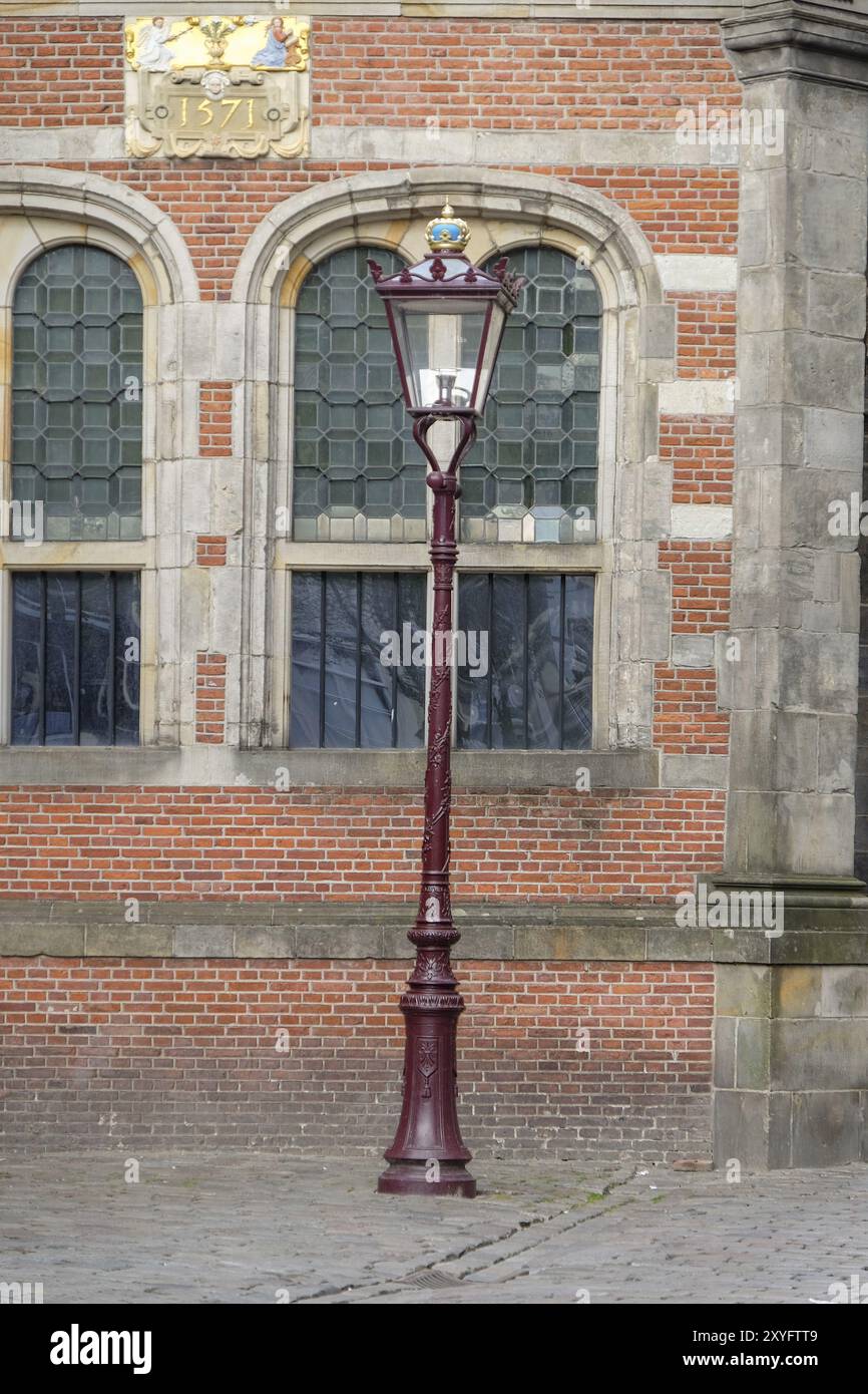 Historischer Laternenpfahl vor einem Backsteingebäude mit großen grün getönten Fenstern, Amsterdam, Niederlande Stockfoto