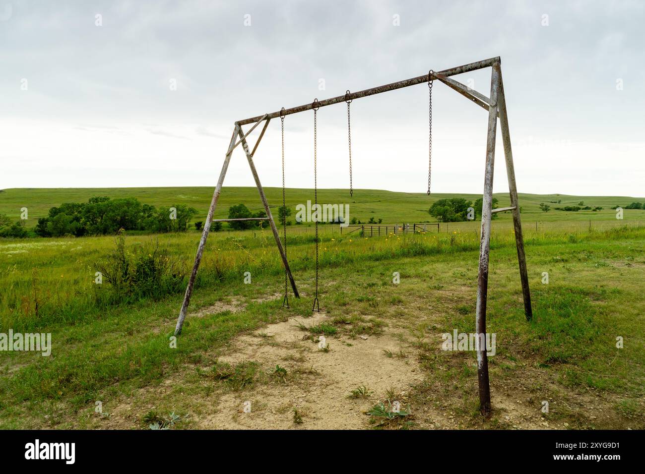 Eine alte hölzerne Schaukel sitzt verlassen auf einer Prärie mit sanften grünen Hügeln in der Ferne Stockfoto