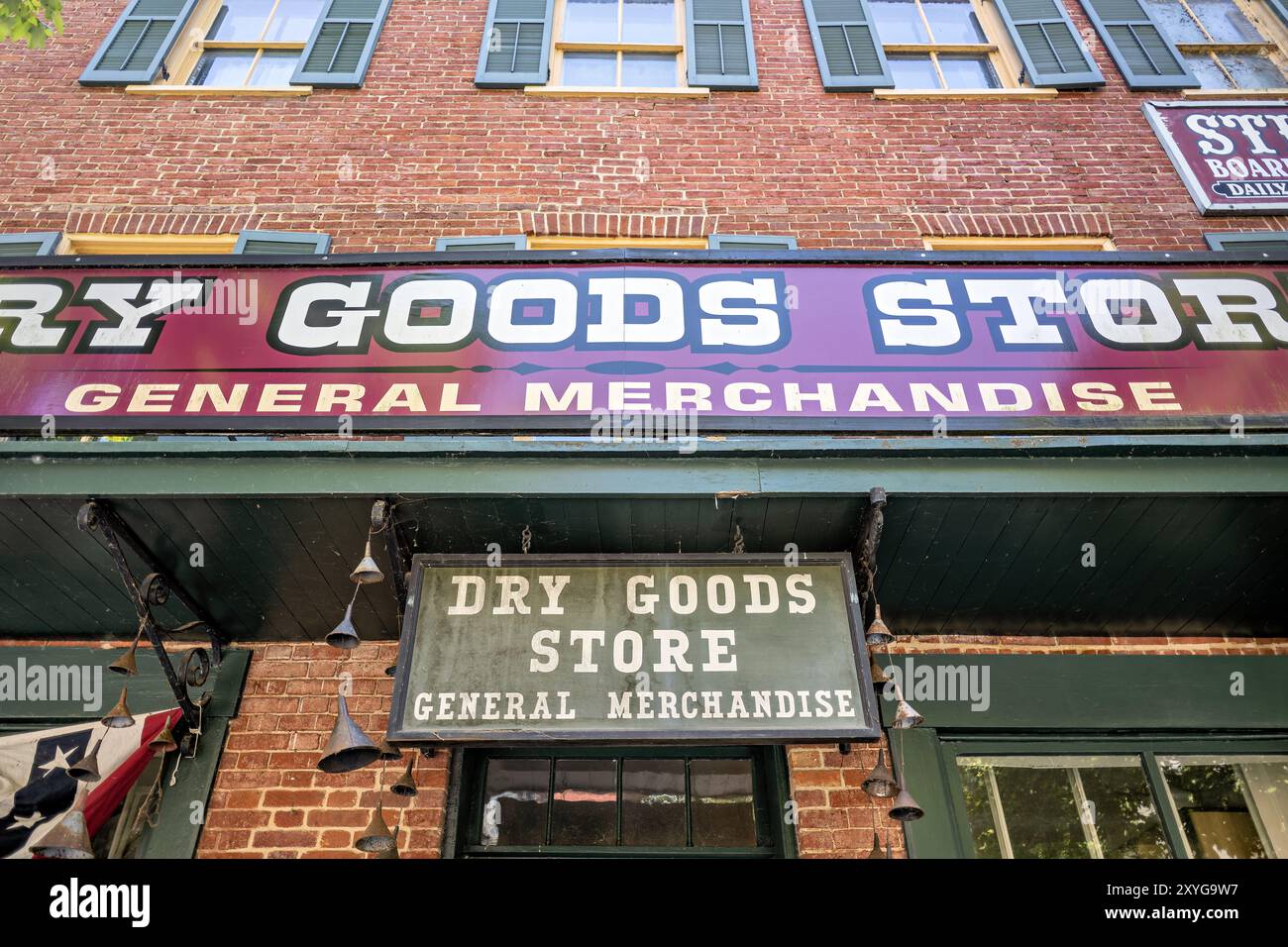 Dry Goods Store General Merchandise Harpers Ferry West Virginia | HARPERS FERRY, West Virginia — Der restaurierte Dry Goods Store, ein Gemischtwarenladen im Lower Town Harpers Ferry, ist Teil des Harpers Ferry National Historical Park. Dieses Gebäude aus dem 19. Jahrhundert verfügt über eine zeitgenössisch genaue Fassade und Ausstellungen, die Besuchern einen Einblick in das Handelsleben einer amerikanischen Stadt vor dem Bürgerkrieg bieten. Die erhaltene Architektur des Ladens und das sorgfältig kuratierte Interieur zeigen die Arten von Waren und Einkaufserlebnissen, die Mitte des 19. Jahrhunderts üblich waren. Die Backsteinfassade und die Holzläden des Gebäudes Stockfoto