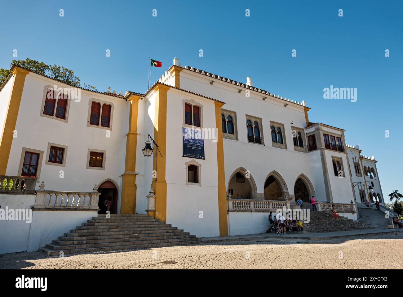 Palácio Nacional de Sintra Portugal // SINTRA, Portugal – das Palácio Nacional de Sintra steht in dieser historischen portugiesischen Stadt, die zum UNESCO-Weltkulturerbe gehört. Der Palastkomplex zeigt die architektonische Entwicklung der portugiesischen Königsresidenzen mit seinen charakteristischen zwei konischen Kaminen, die die mittelalterlichen Küchenviertel kennzeichnen. Die Landschaft von Sintra besticht durch eine vielseitige Mischung aus architektonischen Stilen, darunter gotische, maurische und Renaissance-Elemente in den engen Gassen und an den Hügeln gelegenen Gebäuden. Die Stadt diente als Sommerrefugium für portugiesische Könige Stockfoto
