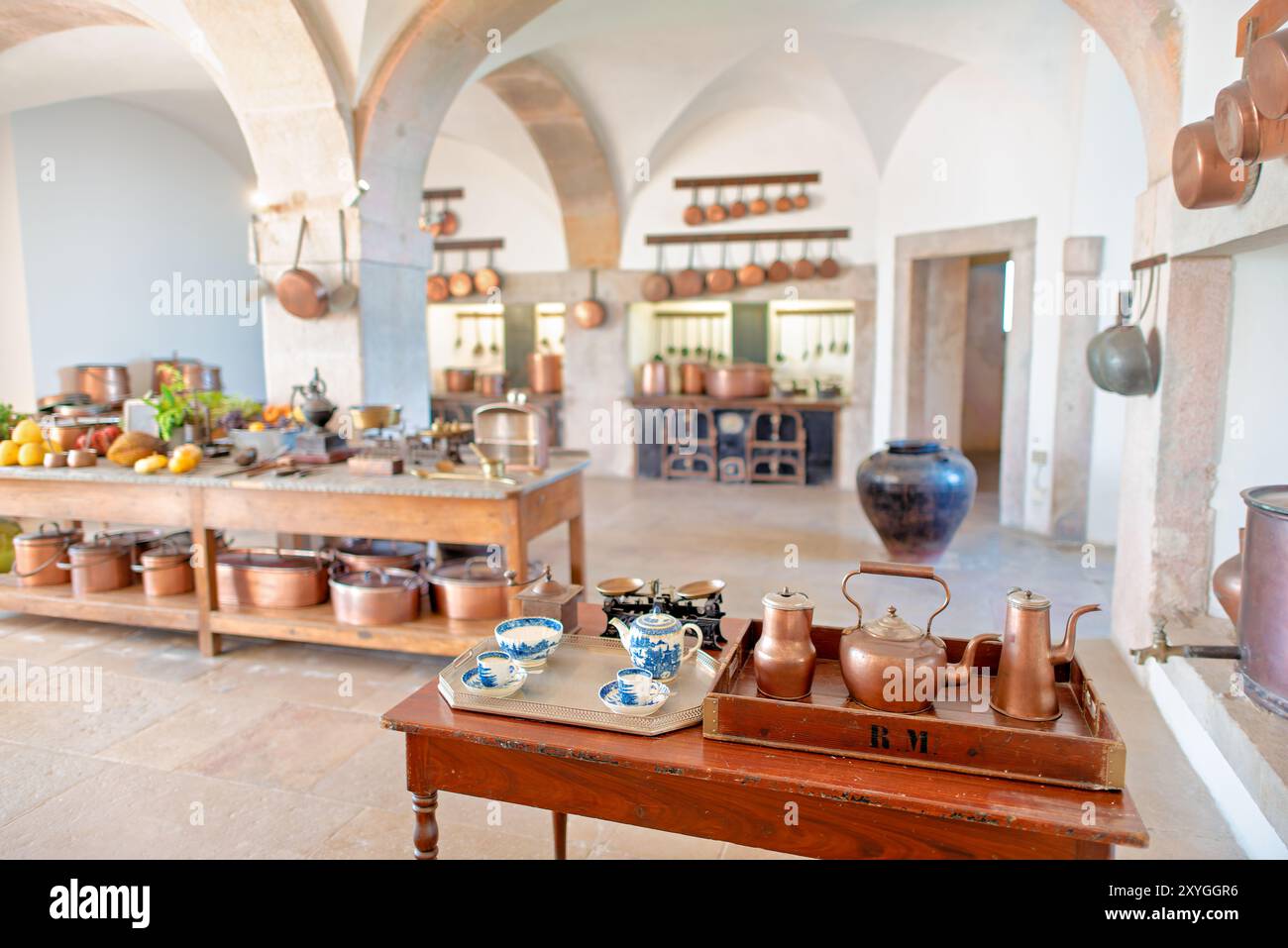 Pena Palace Kitchen Kupfer Kochgeschirr Sintra Portugal // SINTRA, Portugal — die große Küche im Pena Palace mit einer beeindruckenden Auswahl an Kupferkochgeschirr und Kochmöglichkeiten aus dem 19. Jahrhundert. Dieser gut erhaltene Raum bietet Besuchern einen Einblick in die kulinarischen Aktivitäten eines königlichen Haushalts mit seinem weitläufigen Herd, den kunstvollen Fliesen und den glänzenden Utensilien, die den opulenten Charakter des Palastes und die fortschrittlichen Kochtechnologien der Zeit widerspiegeln. Stockfoto