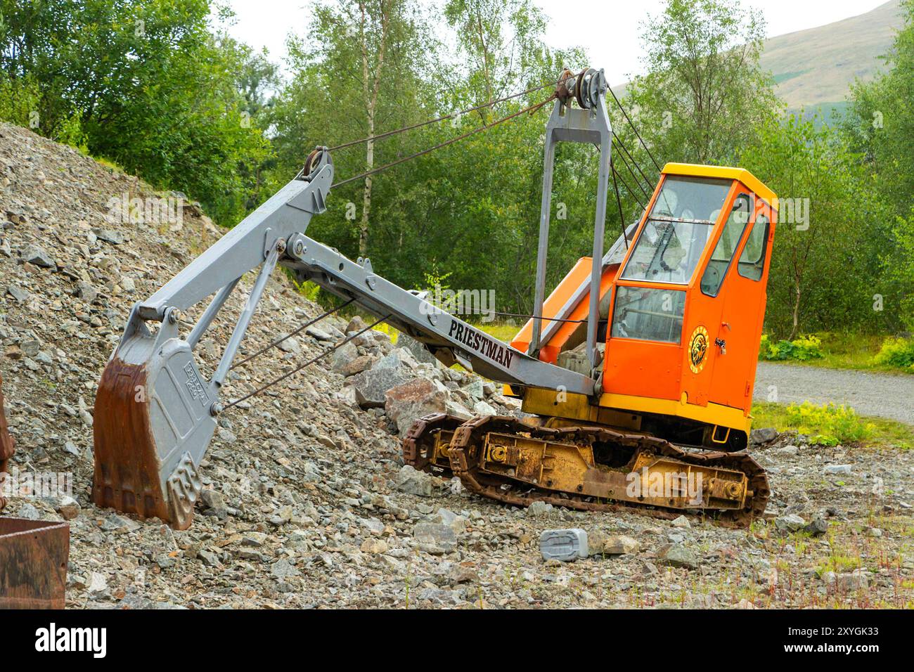 Alter Bagger Priestman „Cub“ Schaufel auf einer felsigen Oberfläche in einer grünen Umgebung mit Steinbruch Bergbaumuseum cumbria uk Stockfoto