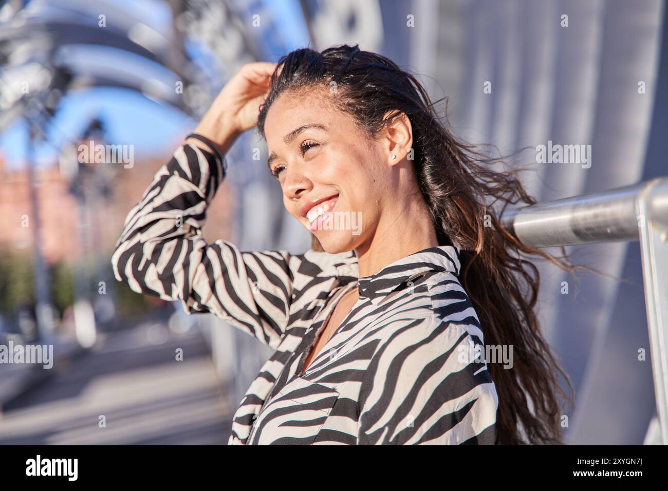 Junge Latina mit langen, brünetten Haaren, die lächeln und ihre weißen Zähne zeigen Stockfoto