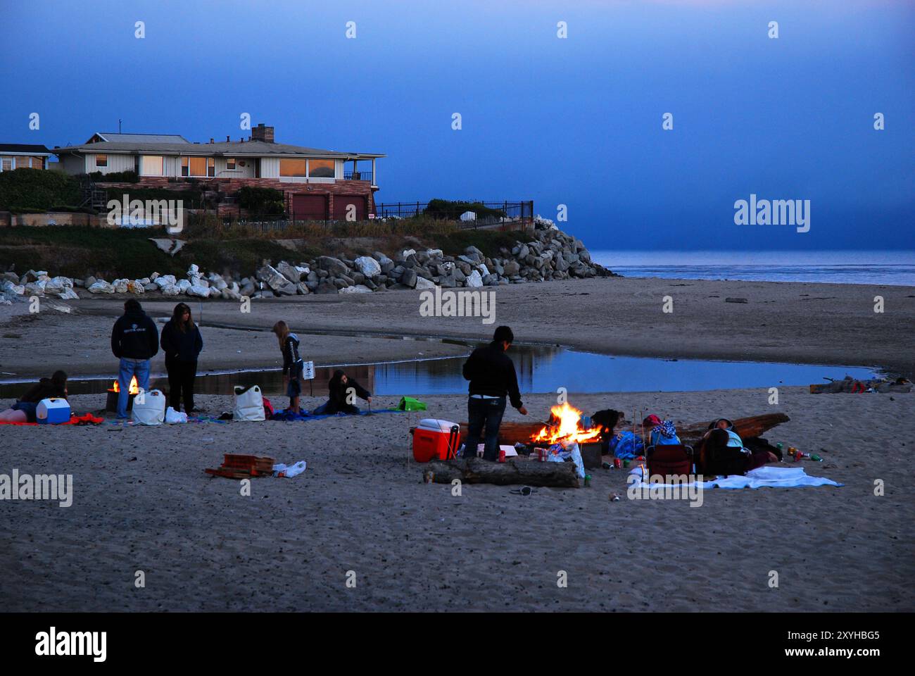 Familie und Freunde beginnen ein Lagerfeuer, um Hot Dogs zu kochen und Marshmallows am Strand in Santa Cruz, Kalifornien, zu braten Stockfoto