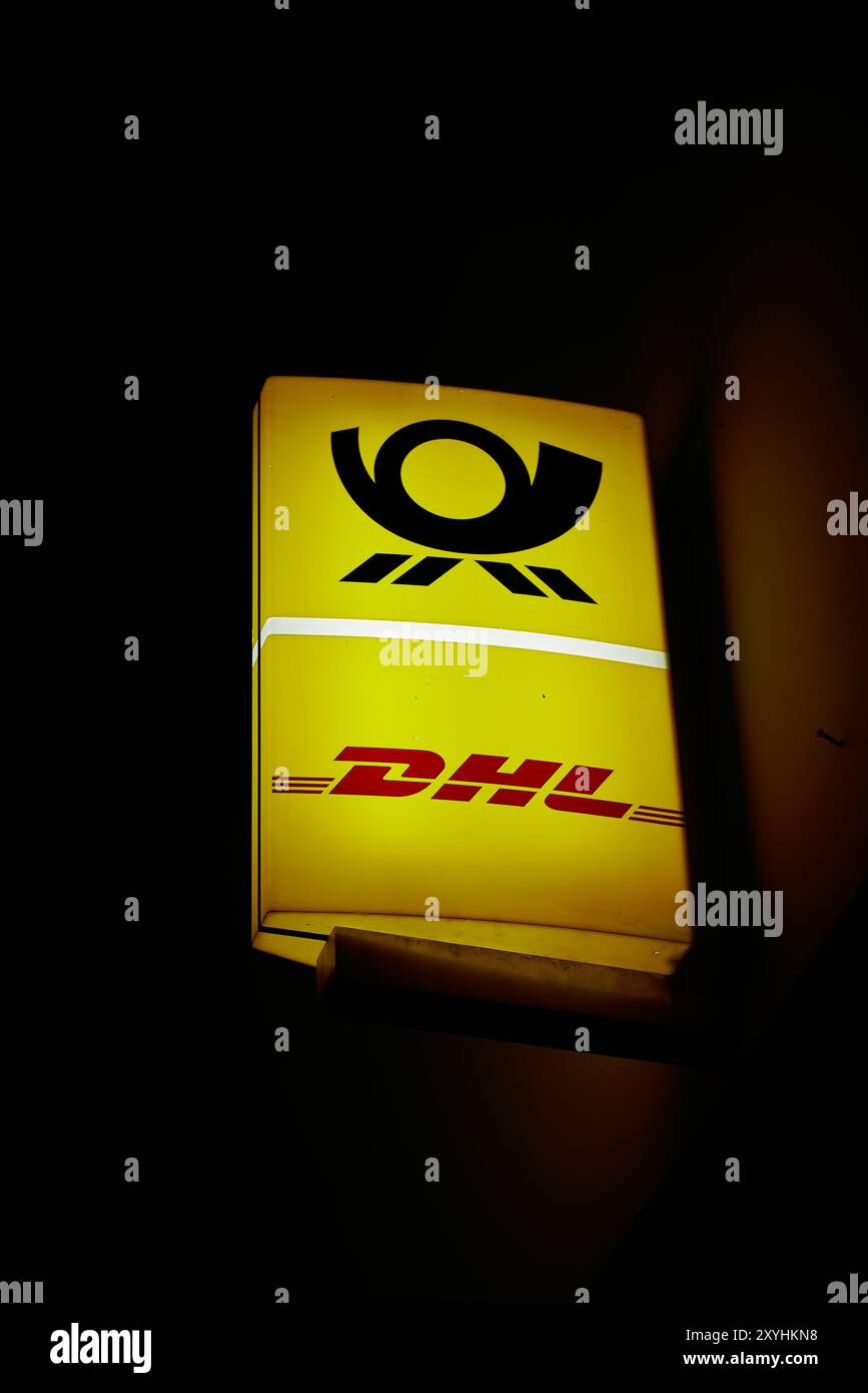 Leuchtschild eines Postamtes des deutschen Logistikunternehmens DHL in Berlin am Abend Stockfoto