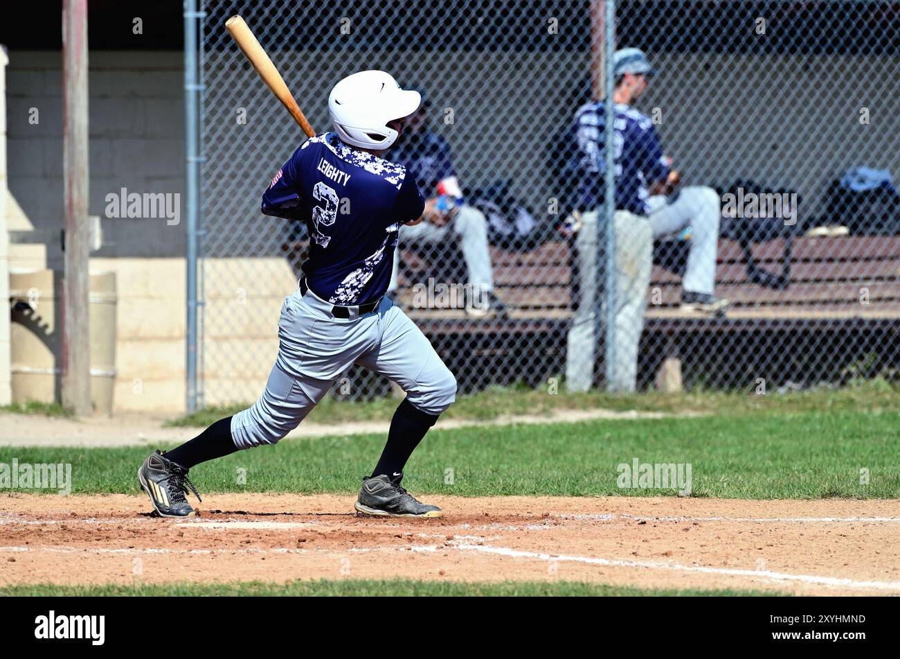 Aurora, Illinois, USA. Ein Batter folgt durch, nachdem er Kontakt hergestellt und eine einzige Tol gefahren hat, verließ das Feld. Während eines Amateur-Baseballspiels für Männer. Stockfoto