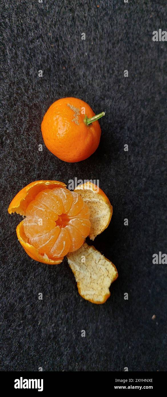 Frische sizilianische Orange, Mandarine mit grünen Blättern auf schwarzem Hintergrund Stockfoto