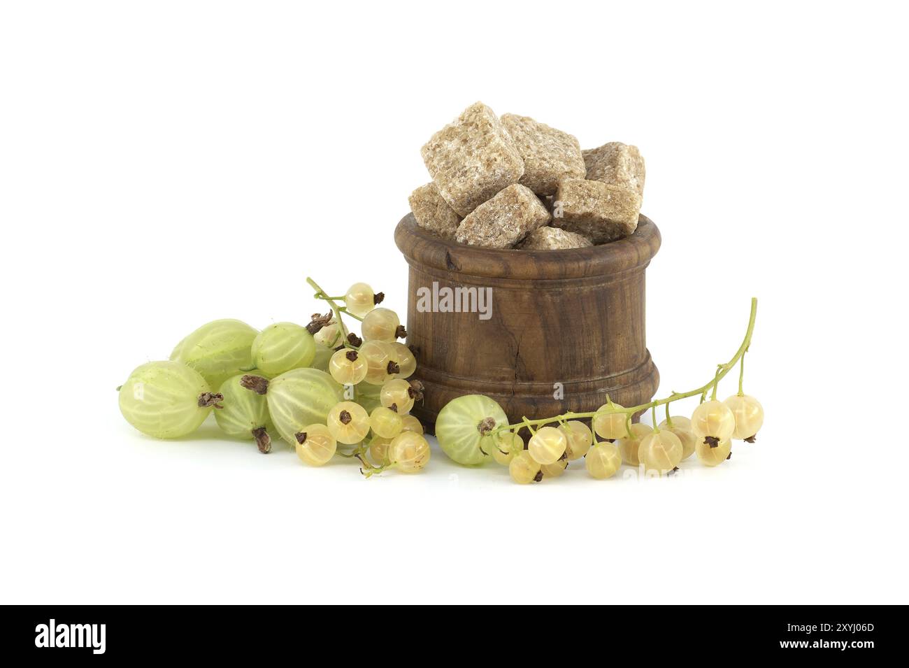 Stachelbeeren und gelbe Johannisbeeren neben braunen Rohrzuckerwürfeln in einer Holzschüssel, isoliert auf weißem Hintergrund, Beerenmarmelade, Kompottzubereitung Stockfoto