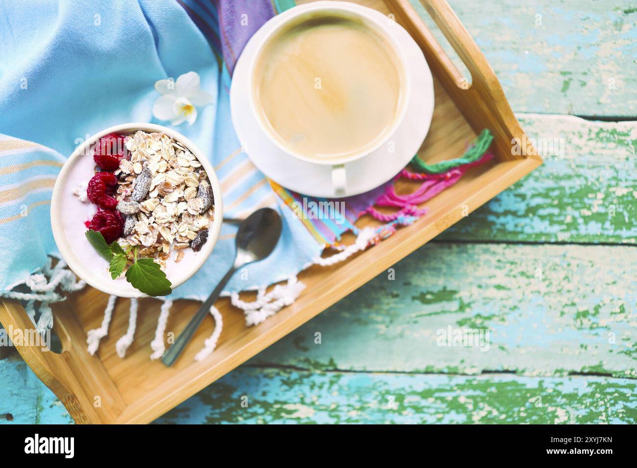 Tasse Müsli mit Joghurt und Obst auf Türkisfarbenem Hintergrund Stockfoto