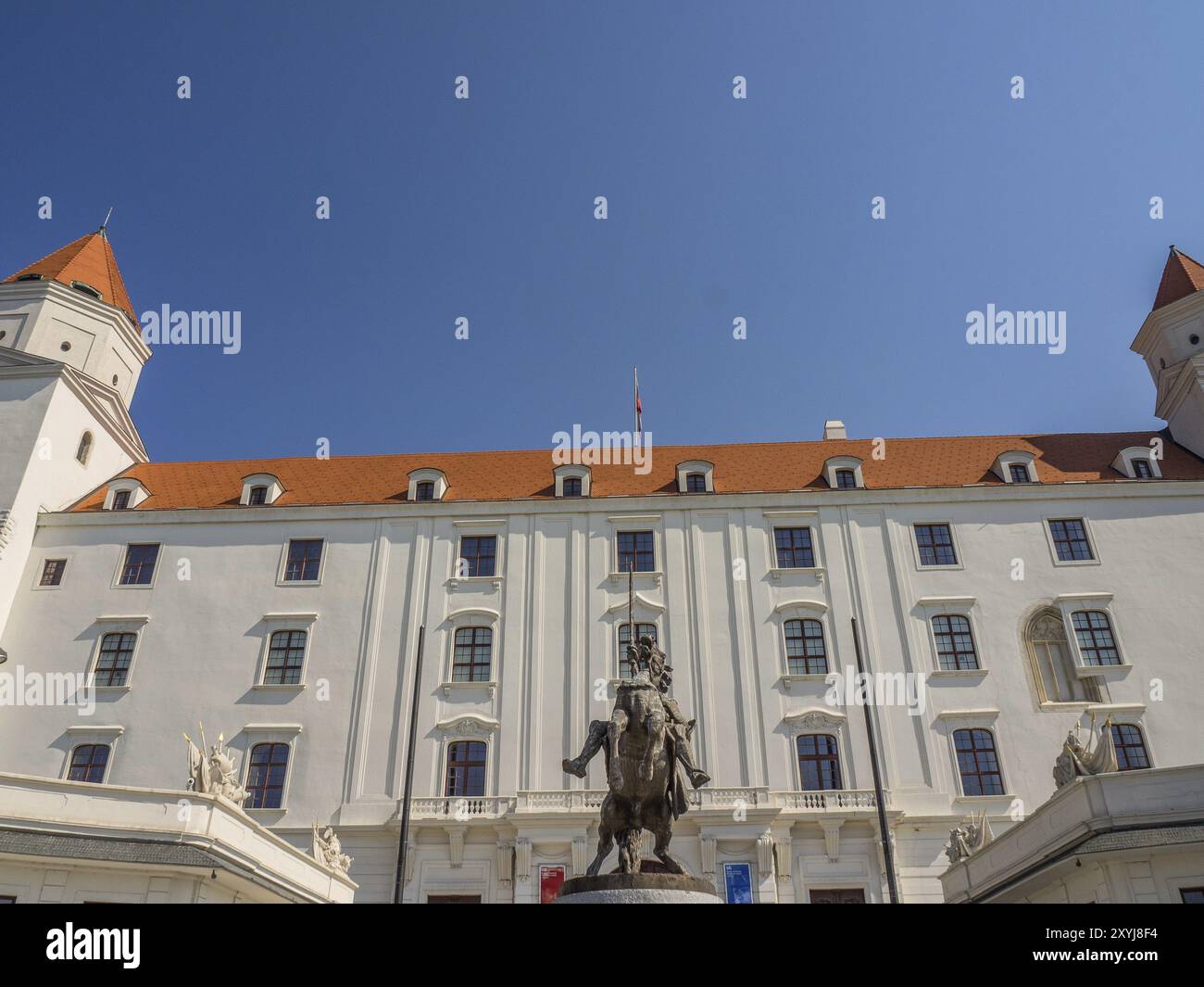 Majestätischer Blick auf eine barocke Burg mit einer Reiterstatue im Vordergrund und blauem Himmel, Bratislava, Slowakei, Europa Stockfoto