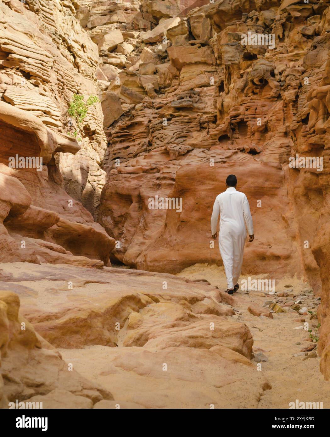 Ein Mann in weißer arabischer Kleidung läuft in einem farbigen Canyon Stockfoto