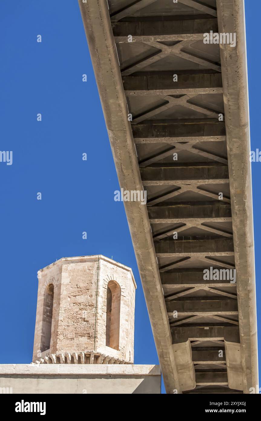 Der Boden einer Fußgängerbrücke aus Beton, von unten gesehen, mit einem alten Wachturm aus Stein auf der linken Seite, alles vor einem blauen Himmel Stockfoto