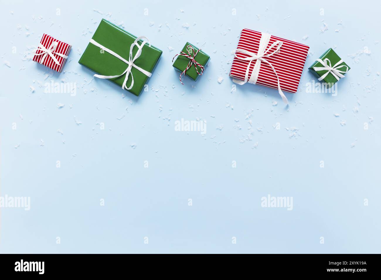 Weihnachten und Neujahr blau flach legen mit verschiedenen roten, weißen und grünen Geschenk-Geschenkboxen Draufsicht. Geschenkband und Verpackungspapier. Dekorieren von Schnee f Stockfoto
