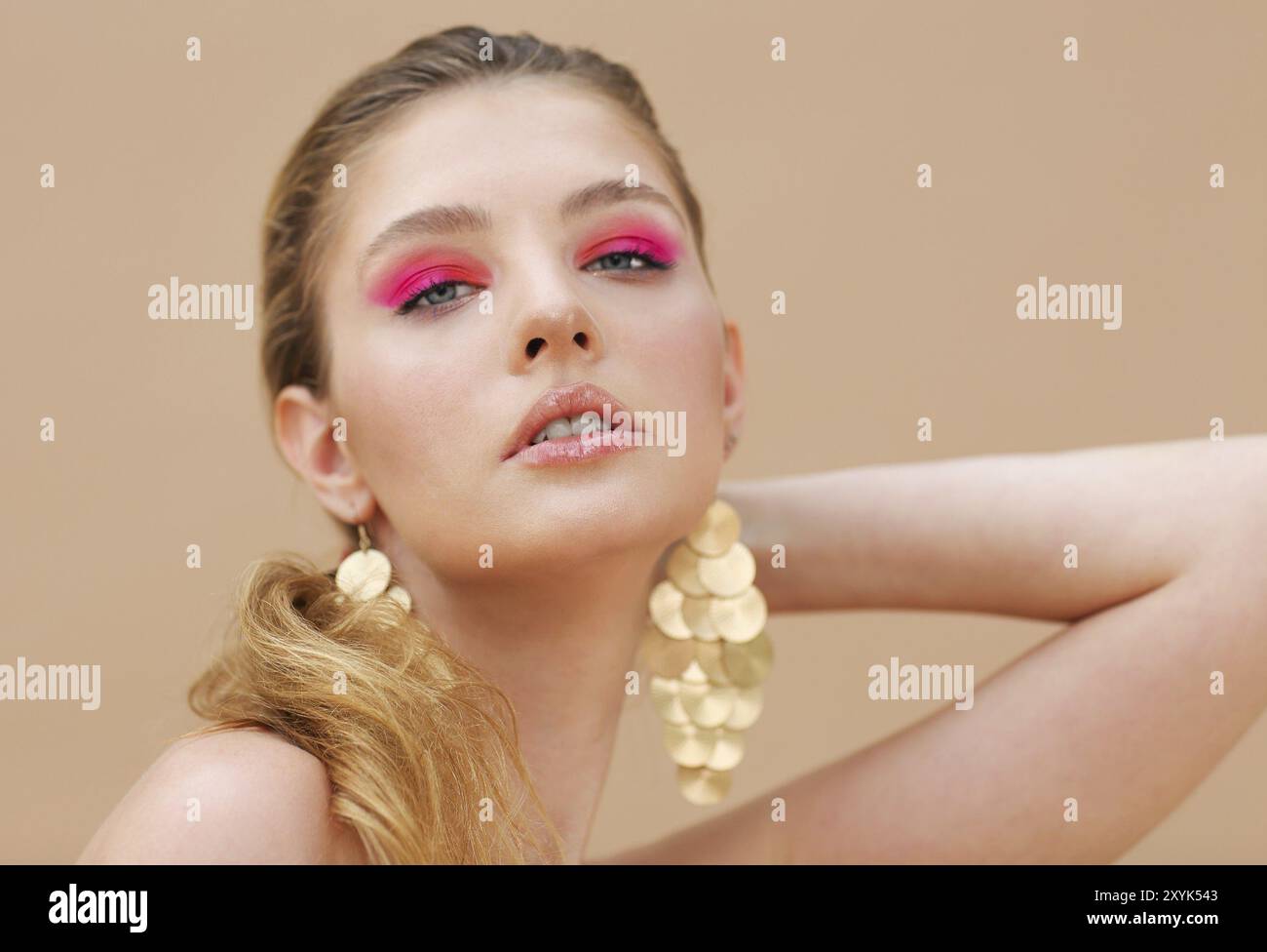 Schönes Modell Mädchen mit roten Maniküre auf die Nägel. Mode helles Make-up und Kosmetik. Das Tragen von großen goldenen Glanz Ohrringe Schmuck Stockfoto