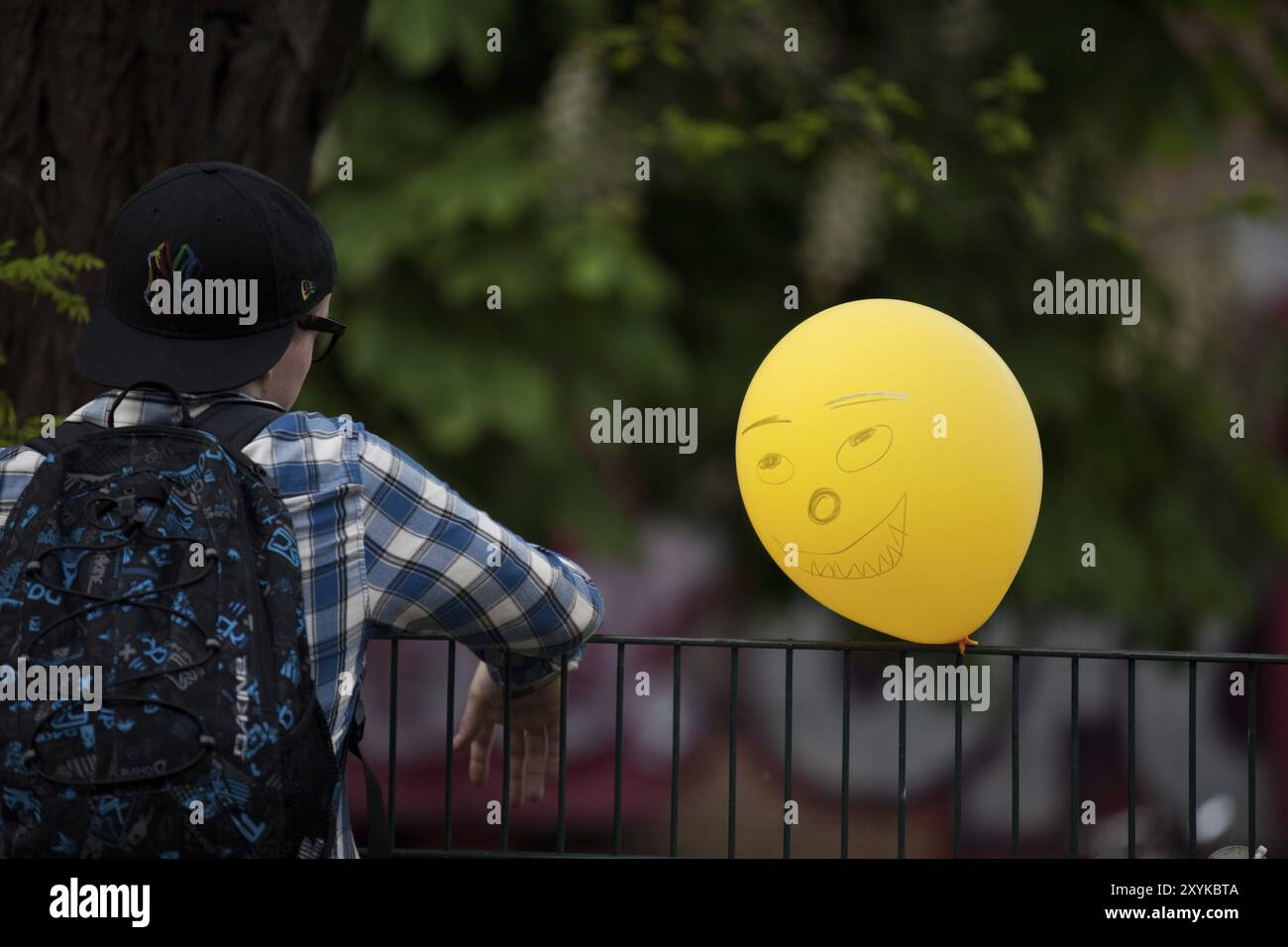 Junge mit einem gelben Ballon mit einem Gesicht drauf Stockfoto