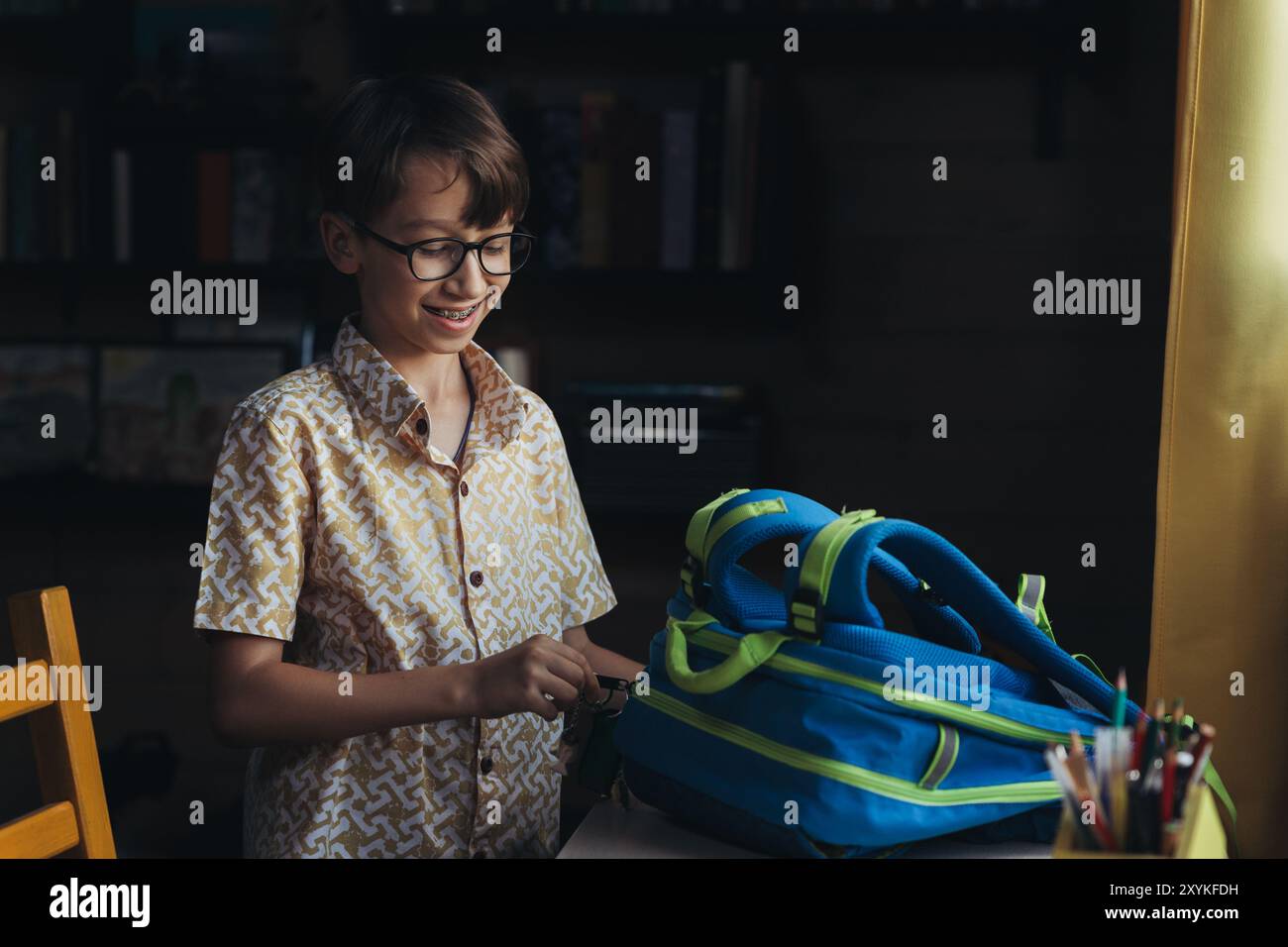 Lächelnder Schuljunge mit Zahnspangen öffnet den Rucksack Stockfoto